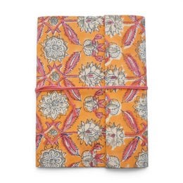 Notebook covered with violet printed fabric featuring floral patterns and designs.
The notebook is covered in a violet-colored printed fabric with a floral pattern. The design includes stylized flowers and leaves in shades of purple, blue, and pink. The fabric has a textured, embroidered-like appearance, adding visual interest to the notebook cover.