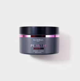 Pomade, a hair wax product, in a black container with pink accents. The pomade is made of natural ingredients and is suitable for styling and shaping hair.