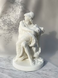 Large, round, white scented candle with a decorative figurine of a seated person.