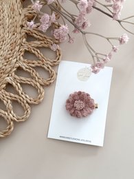  A delicate, handmade flower hair clip in a soft, old pink color. Made of wool, this clip features a floral design that would be a charming accessory for a child's hairstyle.