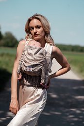Beige and brown baby carrier with safari-inspired design, featuring a wrap-around style and adjustable straps for comfortable wear.