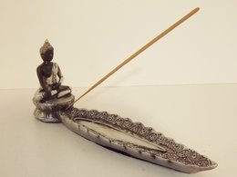 Elongated incense burner with Buddha statue, made of dark material, used for burning incense sticks.