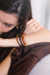 Colorful bangle bracelets in various shades including pistachio, crema, sole, café, caramelo, écaille de tortue, baby blue, baby pink, and nacre.