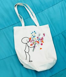 White canvas tote bag with colorful floral design and text "Planner met een dromendoos" (Planner with a dream box).