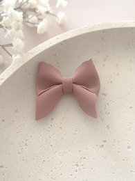 Dusty pink hair clip with a bow design, suitable for kids. The clip is made of a soft, flexible material and has a simple, elegant style.