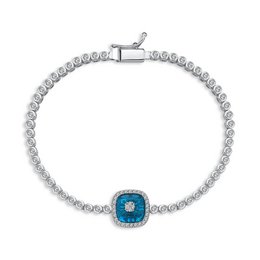 A delicate silver-tone charm bracelet featuring a square-shaped charm with a vibrant blue gemstone at the center, surrounded by a halo of sparkling crystals.
