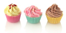 Cupcakes in various flavors including vanilla, strawberry, and chocolate. The cupcakes have colorful frosting and decorations like sprinkles and cherries.