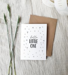 Greeting card with "Hello little one" text in gold foil and stars on a white background, accompanied by a kraft envelope.