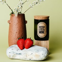 Green glass candle with British strawberry and sparkling wine scent, soy wax, and strawberries.