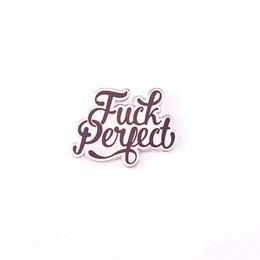 A black and white brooch with the text "Fuck Perfect" in a cursive font.