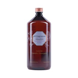 A large glass bottle of laundry detergent with a floral label and a dark brown liquid inside.