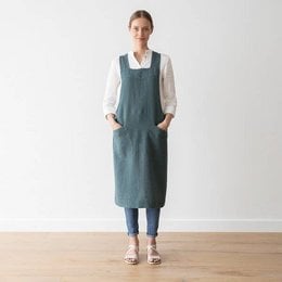 Linen back cross apron in balsam green stone washed color. Durable and stylish apron made of high-quality linen fabric with a cross-back design for a comfortable fit.