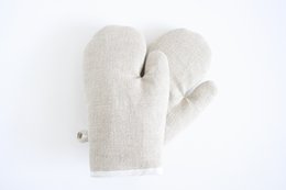 Pair of linen oven gloves, off-white in color, with a simple, minimalist design. Suitable for protecting hands while handling hot items in the kitchen.