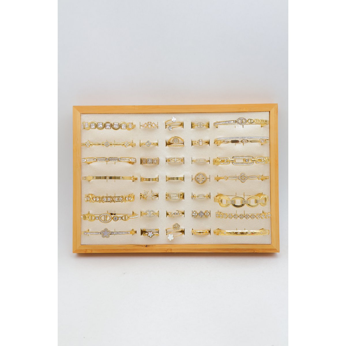 Lot de 21 bagues et 14 bracelets jonc en acier inoxydable sur présentoir.