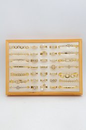 Lot de 21 bagues et 14 bracelets jonc en acier inoxydable sur présentoir.