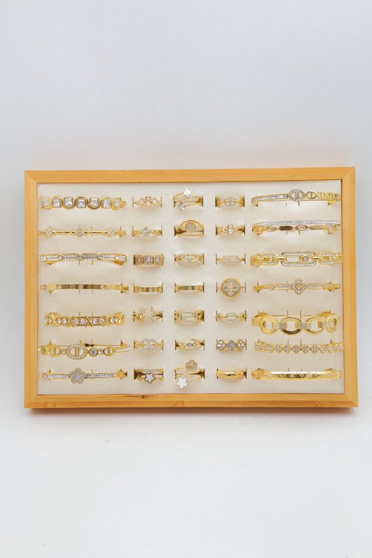 Lot de 21 bagues et 14 bracelets jonc en acier inoxydable sur présentoir.
