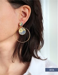 Gold-tone hoop earrings with a circular pendant featuring a floral design.