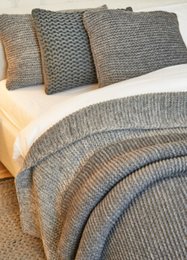 Soft, cozy knitted blanket in ecru-melange and hellgrau-melange colors, made from high-quality merino wool. Measures 190cm x 130cm, perfect for snuggling up on the couch or bed.