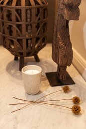 Ceramic candle with rose, vanilla, and amber scents. Tall, round shape with textured surface. Includes product packaging.