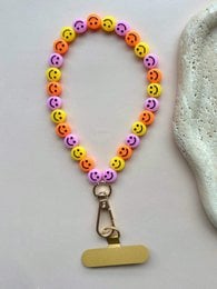 # Product Description
Colorful beaded phone cord with smiley face beads in yellow, red, pink, and green. Metal clasp attachment.