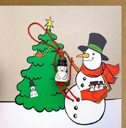 A Christmas card featuring a snowman standing next to a decorated Christmas tree. The snowman is wearing a red scarf and hat, and the tree is adorned with ornaments and a star on top.