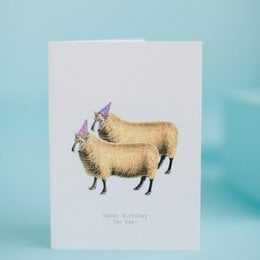 Greeting card with two sheep wearing party hats, celebrating a birthday. The card has a simple, minimalist design with a white background and the text "Happy Birthday to Ewe".
