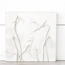 A white wall relief featuring abstract organic shapes and forms, creating a minimalist and modern home decor piece.