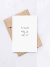 A white greeting card with the text "HATSHIE HATSHOE HATSH!" printed in a minimalist style. The card is accompanied by a brown envelope, suggesting it is a greeting card or invitation.