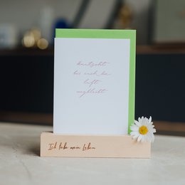  A white card holder with the text "I love my life" printed on it, accompanied by a small daisy flower.