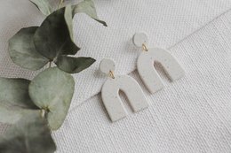 Elegant statement earrings with a modern, minimalist design featuring a simple geometric shape in a neutral tone that complements a variety of outfits.