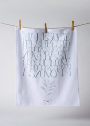A white tea towel with green and black text and a leaf illustration. The text reads "I am some kind of wonderful" in a stylized font.