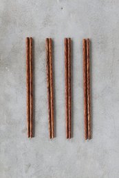 Wooden chopsticks made from coconut material. The chopsticks have a natural, rustic appearance with a warm, reddish-brown color.