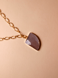 A gold-toned necklace with a dark purple, semi-circular pendant.