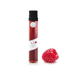 A vibrant red raspberry vinegar in a glass bottle, featuring a fresh raspberry fruit.