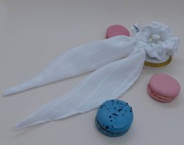 White scrunchie with feather accent, soft and fluffy texture, perfect for adding a touch of whimsy to any hairstyle.