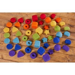 Colorful felt pieces in various shapes and sizes, including circles, triangles, and hexagons, arranged in a rainbow pattern on a wooden surface.