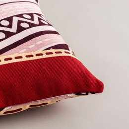 Cushion Fuego Noche, a decorative cushion cover featuring a bold, geometric pattern in shades of red and pink. The cushion cover is available in small, medium, and large sizes.