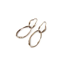 Long, patinated bronze dangle earrings with an elongated oval shape and a statement jewelry design.