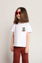 White cotton t-shirt with embroidered crocodile on skateboard design, suitable for kids aged 18 months to 11 years.