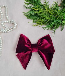 Burgundy velvet hair bow with a large, decorative bow. The bow is made of soft, plush velvet material in a deep burgundy color. It would make a stylish and elegant hair accessory.
