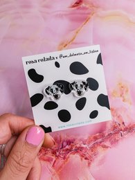 Dalmatian-patterned stud earrings with black and white spots on a pink background.