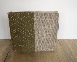  A rectangular toiletry bag made of green and beige fabric with a geometric pattern. The bag has a zipper closure and appears to be made of a durable, textured material.