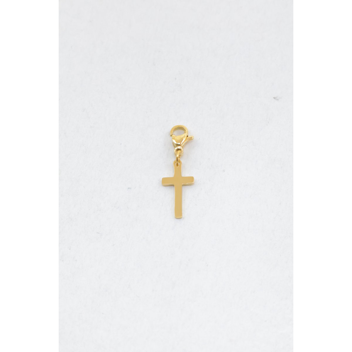 Charm en acier inoxydable. Il se compose d'un pendentif en forme de croix latine à la finition lisse et brillante, surmonté d'un fermoir mousqueton permettant de l'accrocher facilement à un bracelet ou à un collier.