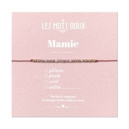 A delicate, pink-colored bracelet with the name "Mamie" written on it. The bracelet appears to be made of beads or threads, with a simple, elegant design.