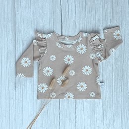 A long-sleeved baby shirt in a floral print pattern with small pink and white flowers. The shirt is made of a soft, lightweight fabric and is suitable for babies and toddlers.