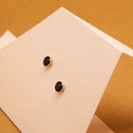 Stud earrings in a variety of colors including blanc, nude, mousse, noir, ambre, brique, midnight blue, prusse, corail, aniline, sable, and massaï. The earrings feature a simple, minimalist design with two small studs.