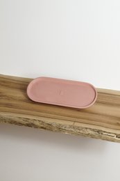 Oval-shaped decorative tray in a soft pink color, made of a durable material and designed to be placed on a wooden surface.