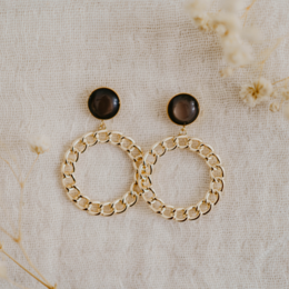 Annelies - Multiple colors available. Statement Earrings with a variety of colors and styles, including round, gold-toned hoops with dark stone accents.