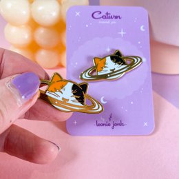  "Gold-plated hard enamel pin in the shape of a planet with a star design. Suitable for wearing as a brooch or pin on clothing."