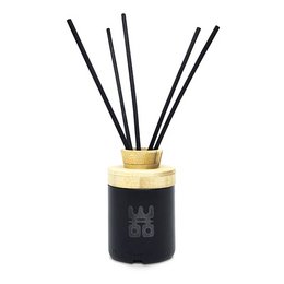 A black reed diffuser with a gold-colored cap and black reed sticks. The diffuser is made from an upcycled vodka bottle and contains a 50 ml fragrance. The product is part of the Treasure and Tranquility collections.